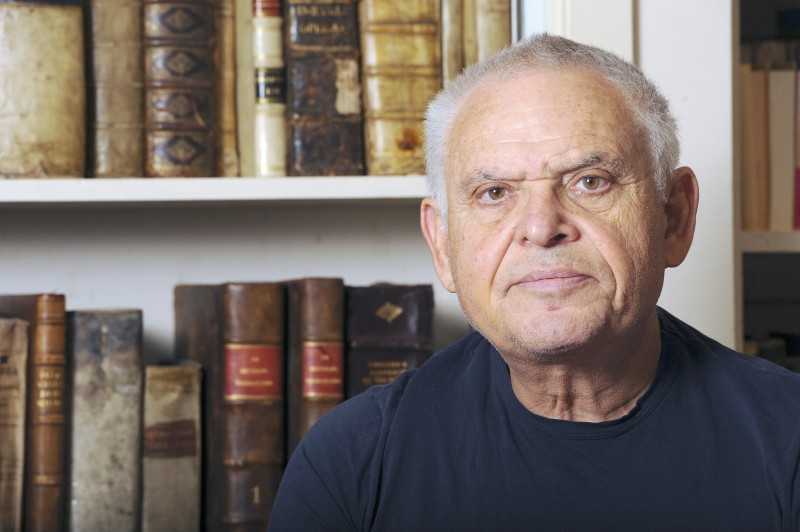 Writer, military & political consultant Edward Luttwak poses in front of a collection of rare books in his home office in Chevy Chase, Maryland on April 8, 2015.