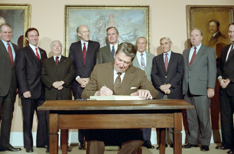 11/6/1986 President Reagan in the Roosevelt Room signing S. 1200 Immigration Reform and Control Act of 1986 with Dan Lungren Strom Thurmond George Bush Romano Mazzoli and Alan Simpson looking on